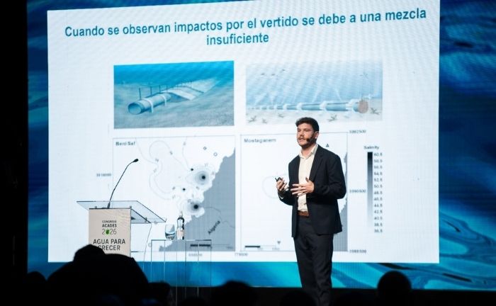Fotografía del profesor Iván Sola presentando en Congreso ACADES 2026 se ve de fondo su presentación