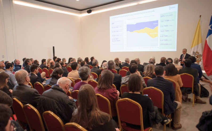 Fotografía de una persona presentando en un salón lleno de gente